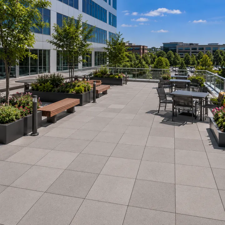 AM Developers LLC built an elevated roof deck with large-format pedestal pavers, glass railings, planters, benches, and rooftop dining.