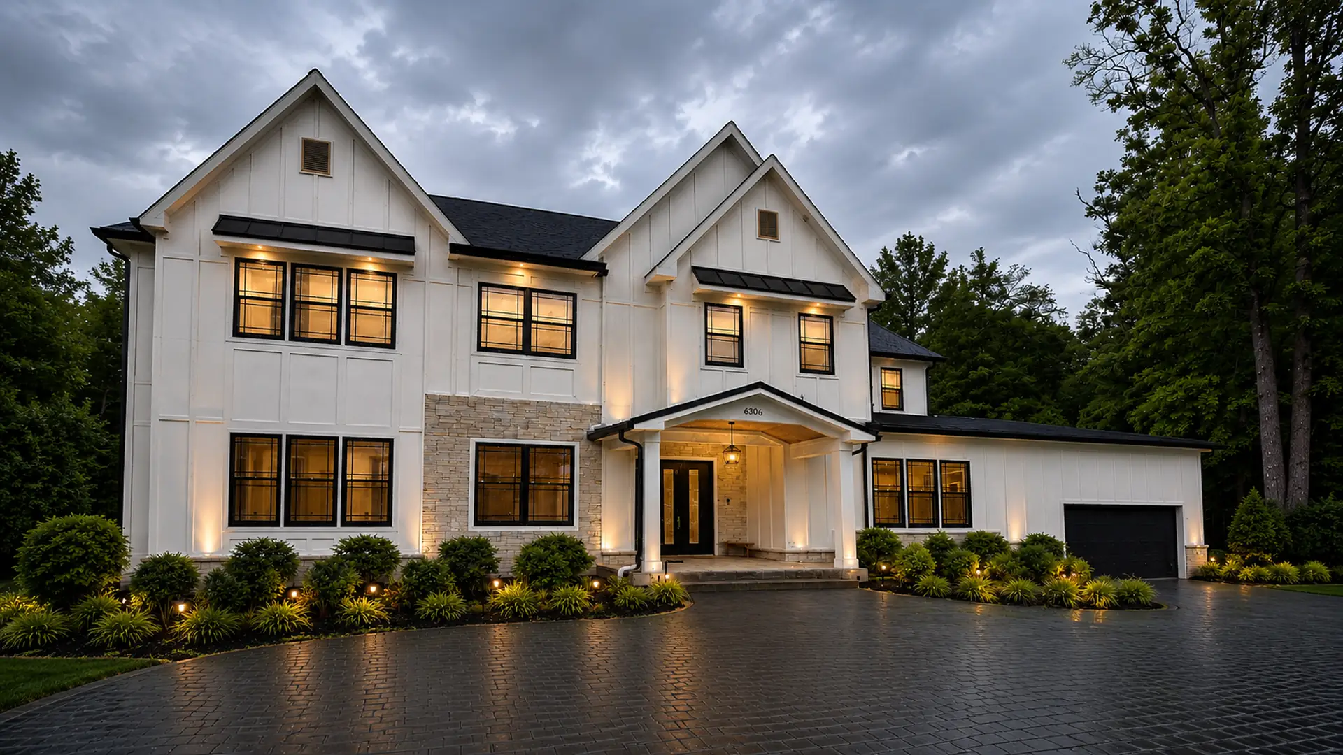 AM Developers LLC built a luxury estate driveway in Boyds, MD, with wide pavers, porch entry, stone facade, black windows, and landscape lighting