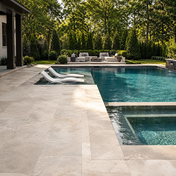 AM Developers LLC installed slip-resistant natural stone pool decking with a raised spa in Reston, VA for safe luxury living