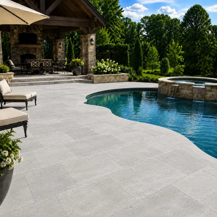 AM Developers LLC, presents a bespoke travertine patio and pool deck installation for a Germantown, Maryland backyard, with light natural stone pavers, curved pool surround, raised spa, coping, outdoor fireplace pavilion, dining terrace, lounge chairs, planting beds, and landscaped retaining edges